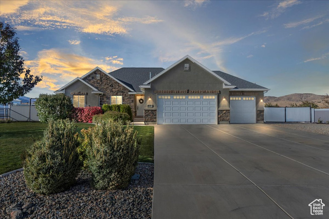 View of front of home with a mountain view, a garage, and a lawn