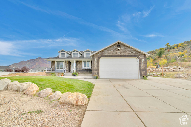 View of front of home with a front yard, a garage, a mountain view, and a porch