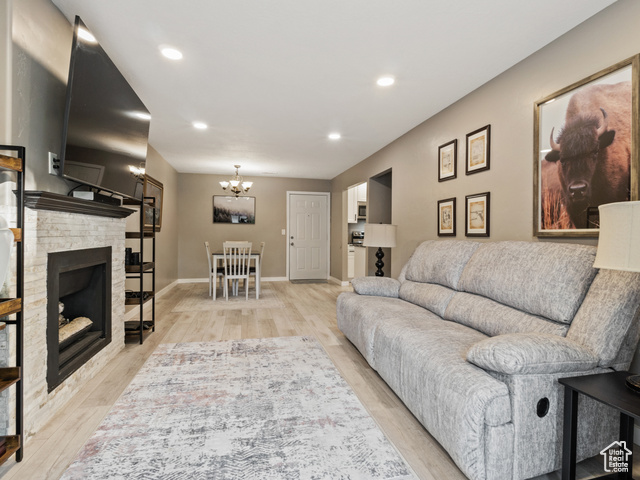 Living room with a chandelier, light wood-type flooring, and a fireplace