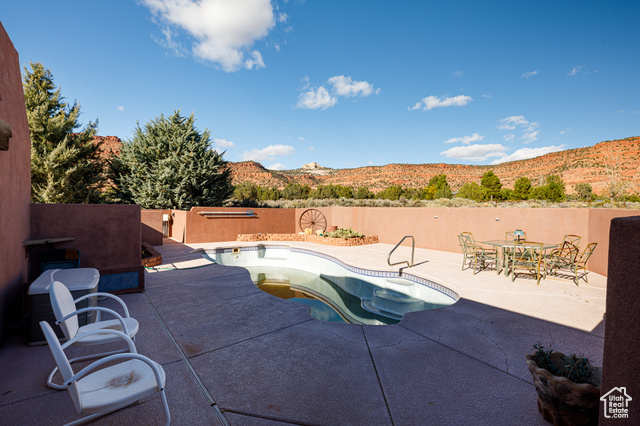 View of swimming pool with a hot tub, a mountain view, and a patio area