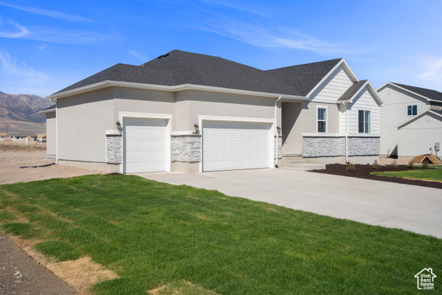 View of front of home featuring a garage, a front lawn, and a mountain view. Photo of a Delaney Home but not the subject property