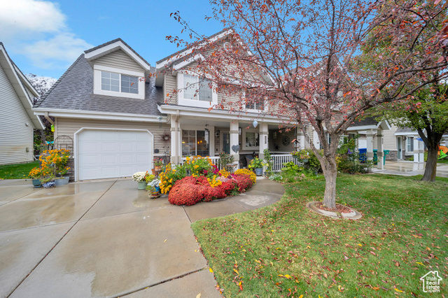 View of front of home with a garage, a front yard, and a porch