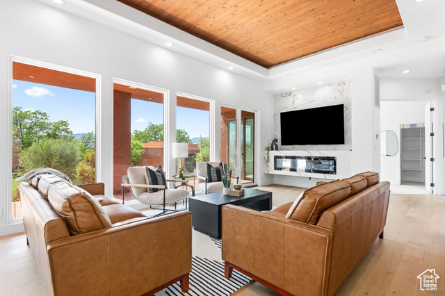 Living room with light hardwood / wood-style flooring, a tray ceiling, and wood ceiling