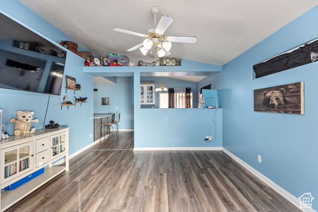 Interior space featuring dark wood-type flooring, ceiling fan, and vaulted ceiling