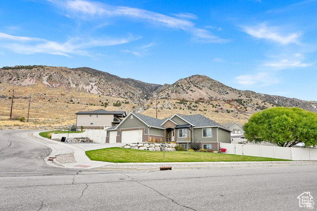 Single story home featuring a mountain view, a front lawn, and a garage