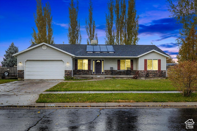 Ranch-style house with a garage, porch, and solar panels