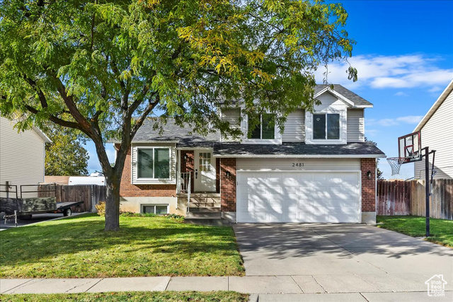 View of front of property featuring a garage and a front lawn