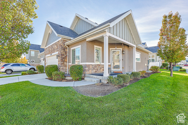 View of front of house with a garage, a front yard, and covered porch