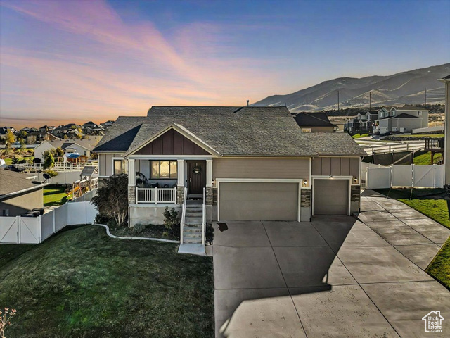 View of front of property with a lawn, a mountain view, and a garage