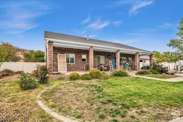 Rear view of property with a lawn and a patio area