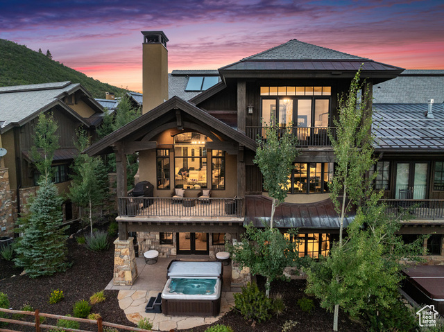 Back house at dusk featuring a balcony and a patio area