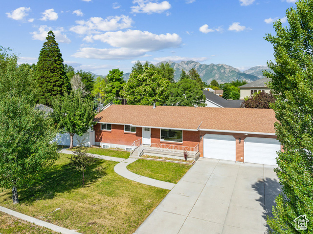 Single story home featuring a fully fenced back yard with gates, front lawn, a mountain view, and 2 SINGLE CAR garages