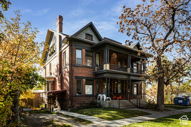 View of front of home with a balcony, a front yard, and a porch