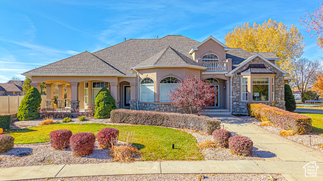 View of front of property with a front yard and a balcony