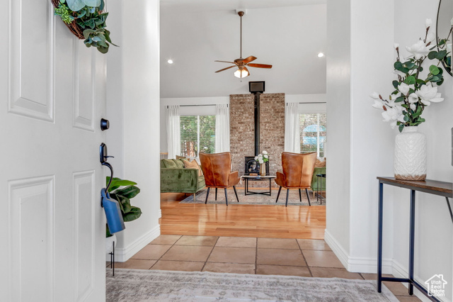 Tiled foyer with ceiling fan, a wood stove, and high vaulted ceiling