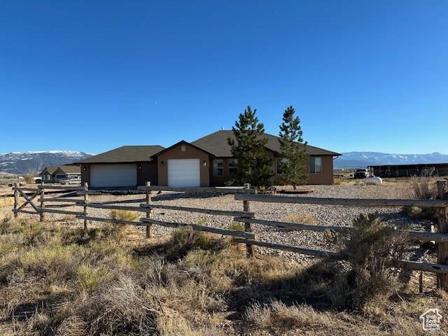 Ranch-style house with a mountain view, a garage, and a rural view