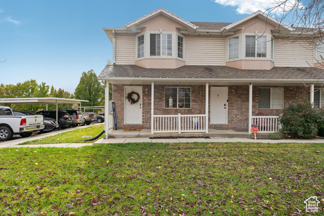 View of front of property with a front yard and a carport