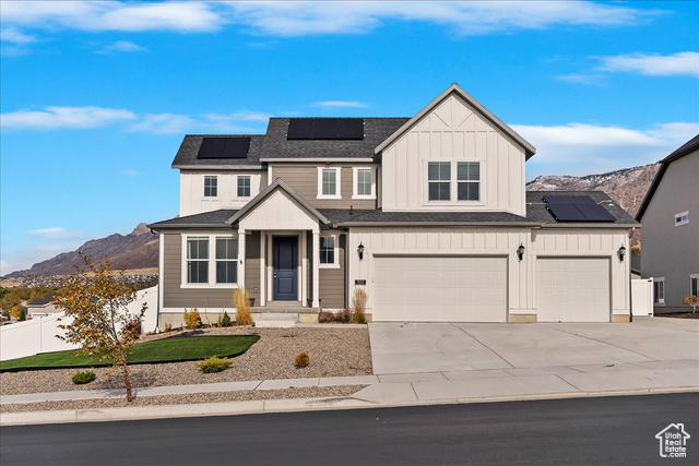 View of front of home featuring solar panels, a mountain view, and a garage