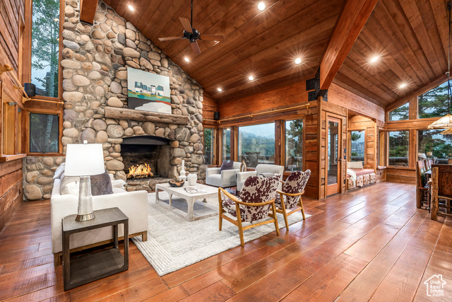 Living room with a fireplace, high vaulted ceiling, hardwood / wood-style flooring, and beamed ceiling