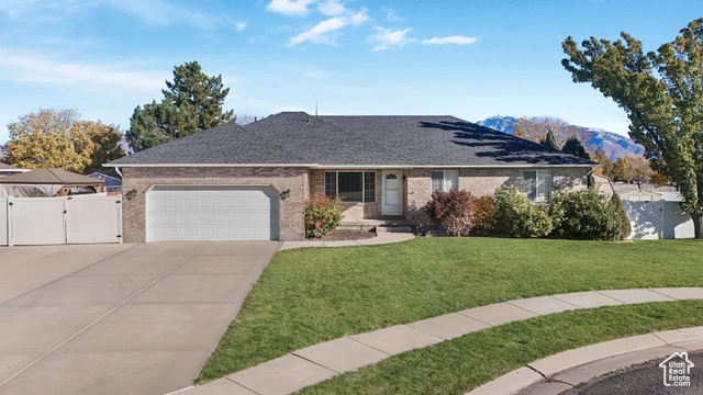 Ranch-style home featuring a garage, a front lawn, and a mountain view