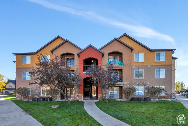 View of front facade featuring a balcony and a front lawn