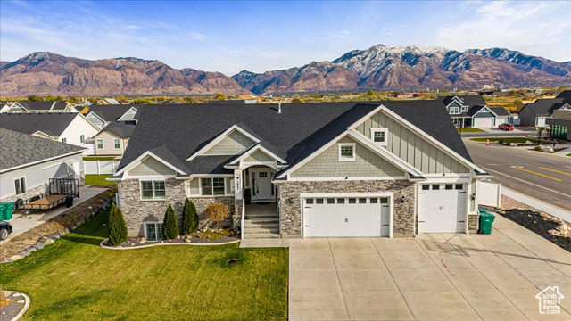 View of front of property with a mountain view, central air condition unit, a garage, and a front yard