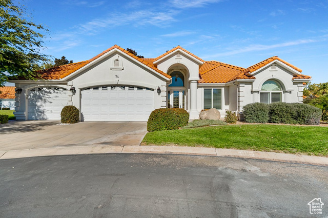 Mediterranean / spanish home with a front yard and a garage