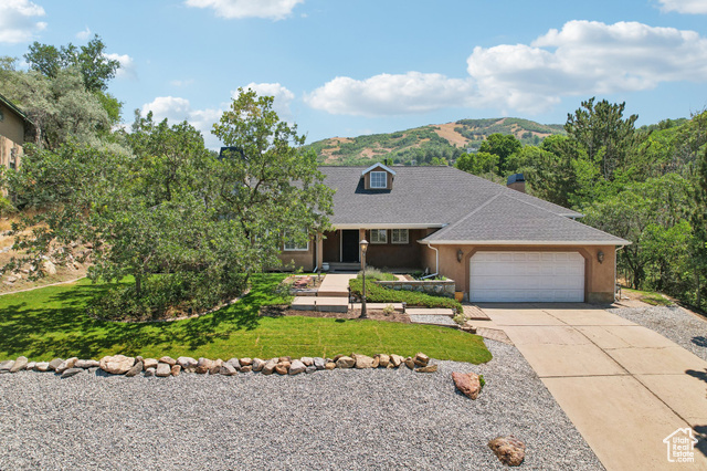 View of front of house featuring a mountain view, a garage, and a front yard