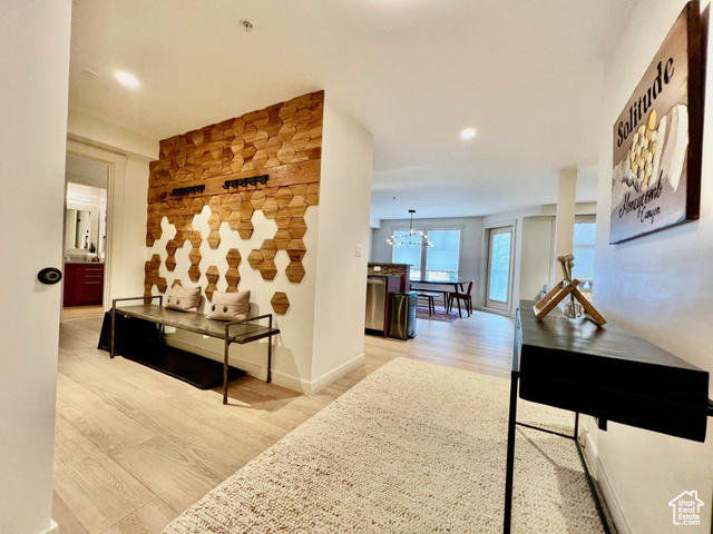 Hall with light hardwood / wood-style flooring and a notable chandelier