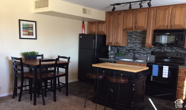 Kitchen featuring black appliances, butcher block countertops, sink, and tasteful backsplash