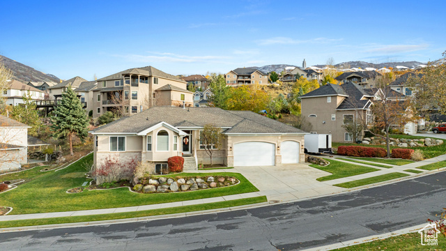 View of front of home featuring a mountain view, a front yard, and a garage