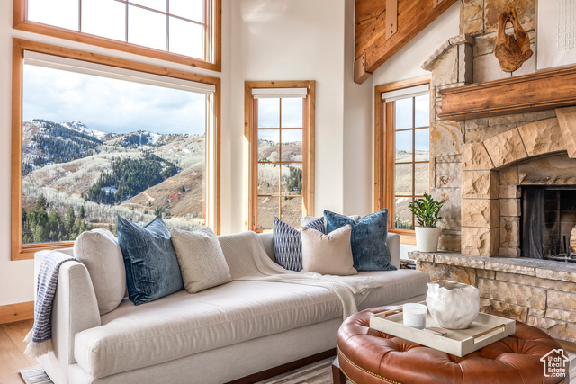 Living room featuring a mountain view, hardwood / wood-style floors, high vaulted ceiling, and a stone fireplace