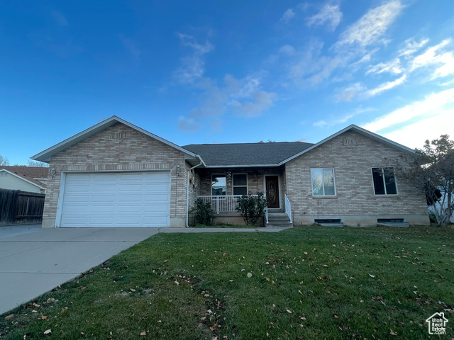 Ranch-style home featuring covered porch, a garage, and a front yard