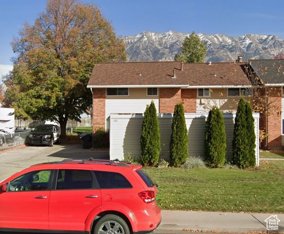 View of front of house with a mountain view and a front lawn