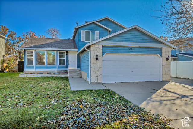 View of front of home with a garage and a front lawn