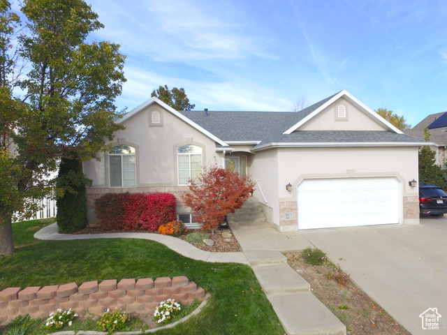 Single story home featuring a garage and a front lawn