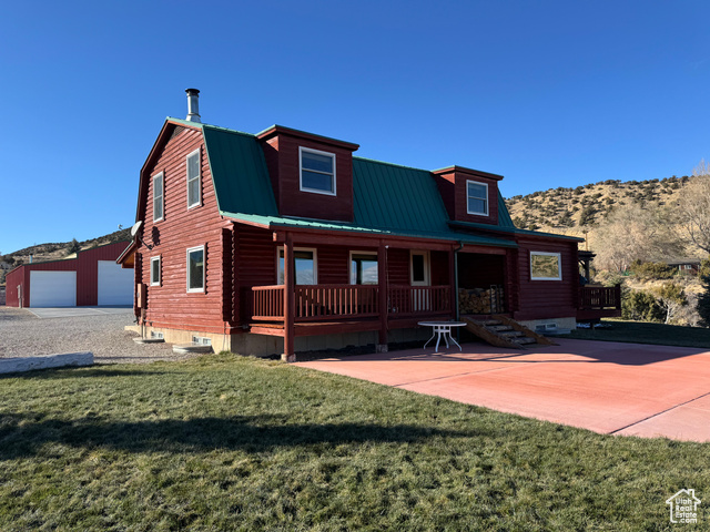 View of front of house featuring a porch, a garage, an outdoor structure, and a front yard