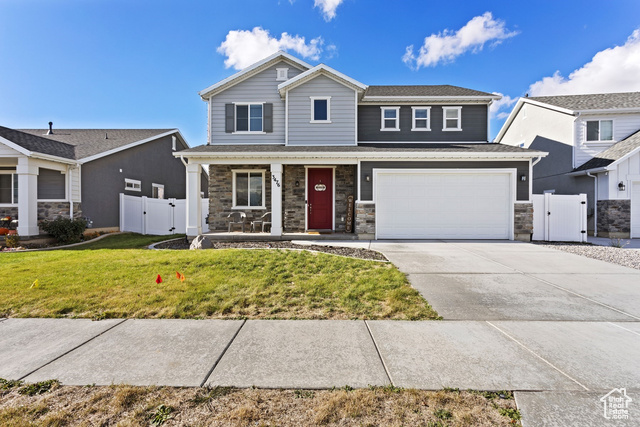 View of front of home featuring a garage, a porch, and a front yard