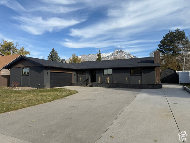 Ranch-style home featuring a garage and a front yard with mountains in background