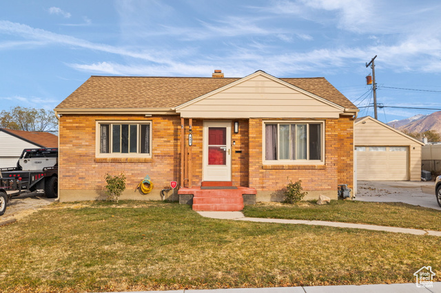 Bungalow-style home with a garage, an outdoor structure, and a front yard