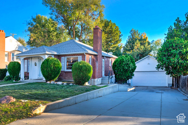 View of front of property with a garage, an outbuilding, and a front yard