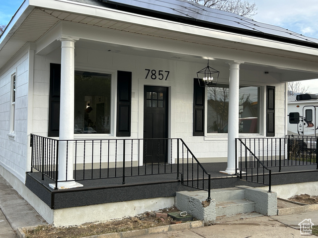 Doorway to property featuring solar panels and a porch