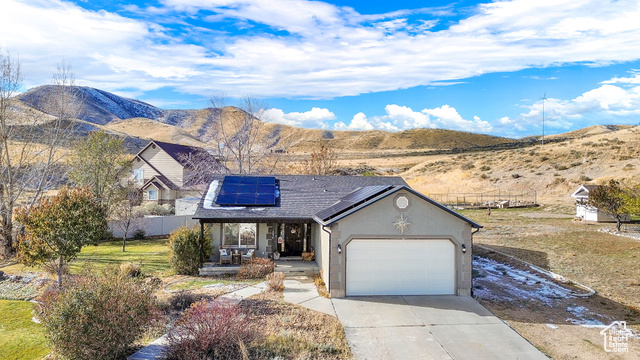 View of front of home featuring a mountain view, solar panels, a garage, and a porch