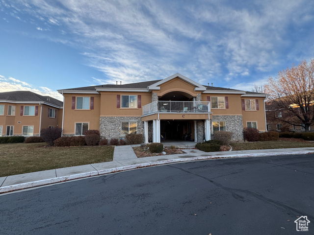 View of front of property with a front yard and a balcony