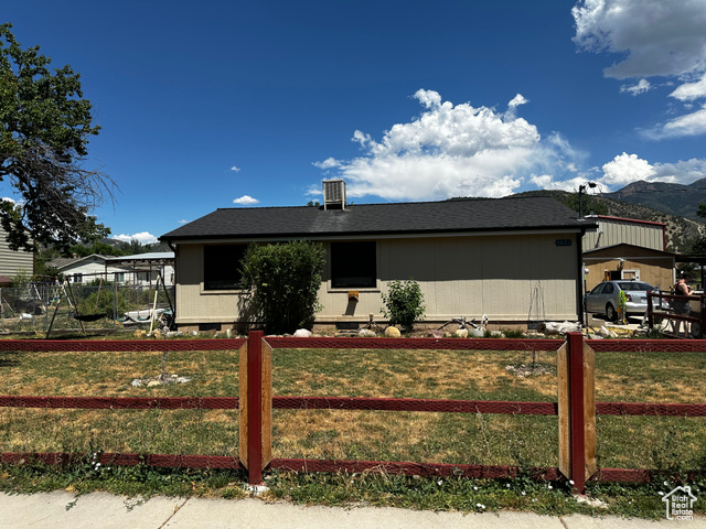 View of side of home featuring a mountain view, a yard, and a trampoline