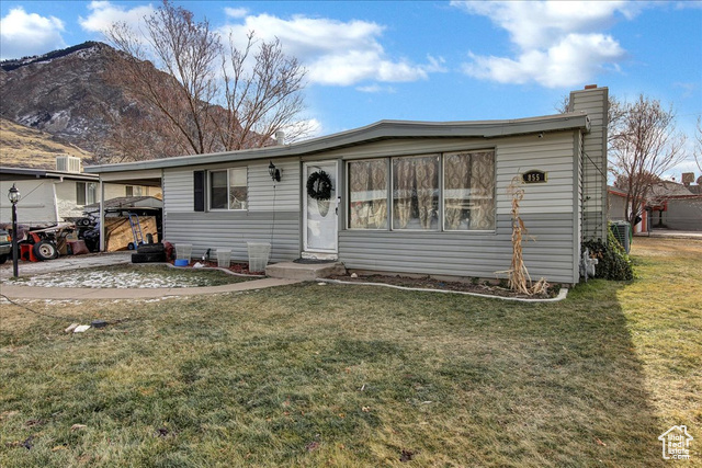 View of front of home with a front yard, a mountain view, and a carport