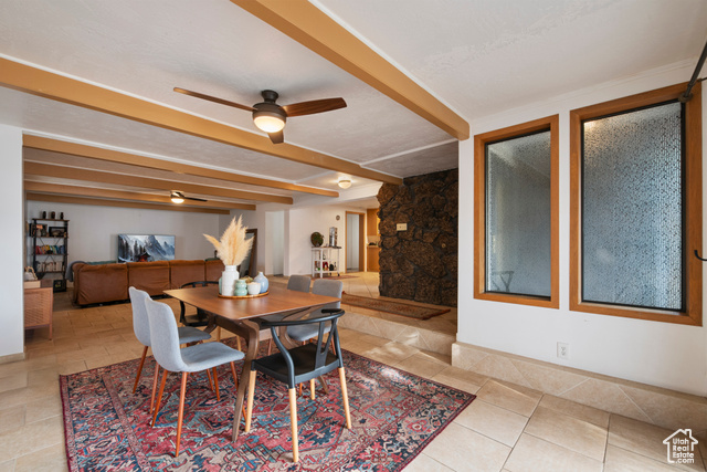 Dining area featuring beam ceiling, ceiling fan, and a textured ceiling