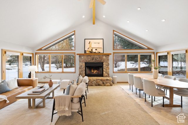 Living room featuring beam ceiling, a stone fireplace, high vaulted ceiling, and french doors