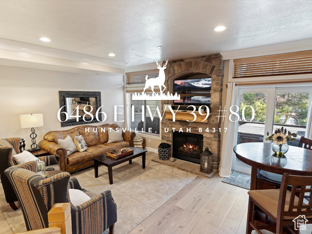 Living room featuring a fireplace, a textured ceiling, light hardwood / wood-style floors, and ornamental molding