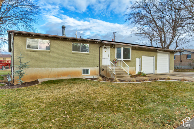 View of front of property featuring a front yard and a garage